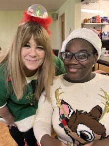 Resident Mapalo with project worker Mel smiling wearing Christmas jumpers