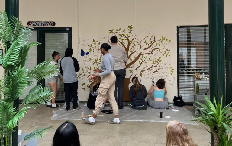 A group of 6 young residents painting and helping with the artwork for the new mural