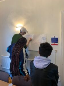 Three members of the youth council writing their ideas on a white board