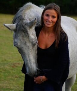 Chantal smiling with a white horse leaning over her sholder. Chantal is nominated for Young Leader Award. 