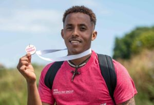 Temesgen, nominated for Young Volunteer award, smiling holding up his medal for the downslink challenge