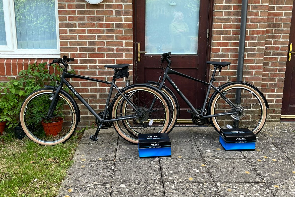 Two new bikes and helmets in the garden leaning against a brick wall