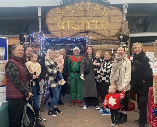 Our Young families and staff from the project stood in a line under the 'Stanta's grotto' sign with Clive dressed as a green elf