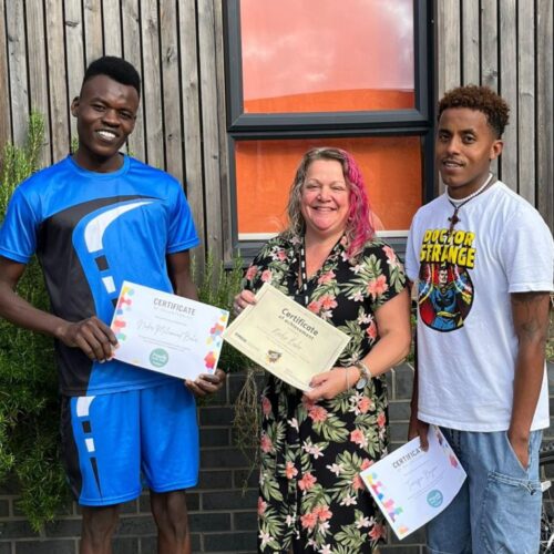Temesgen and Nader holding certificates with their Inspire Coach Jessica smiling