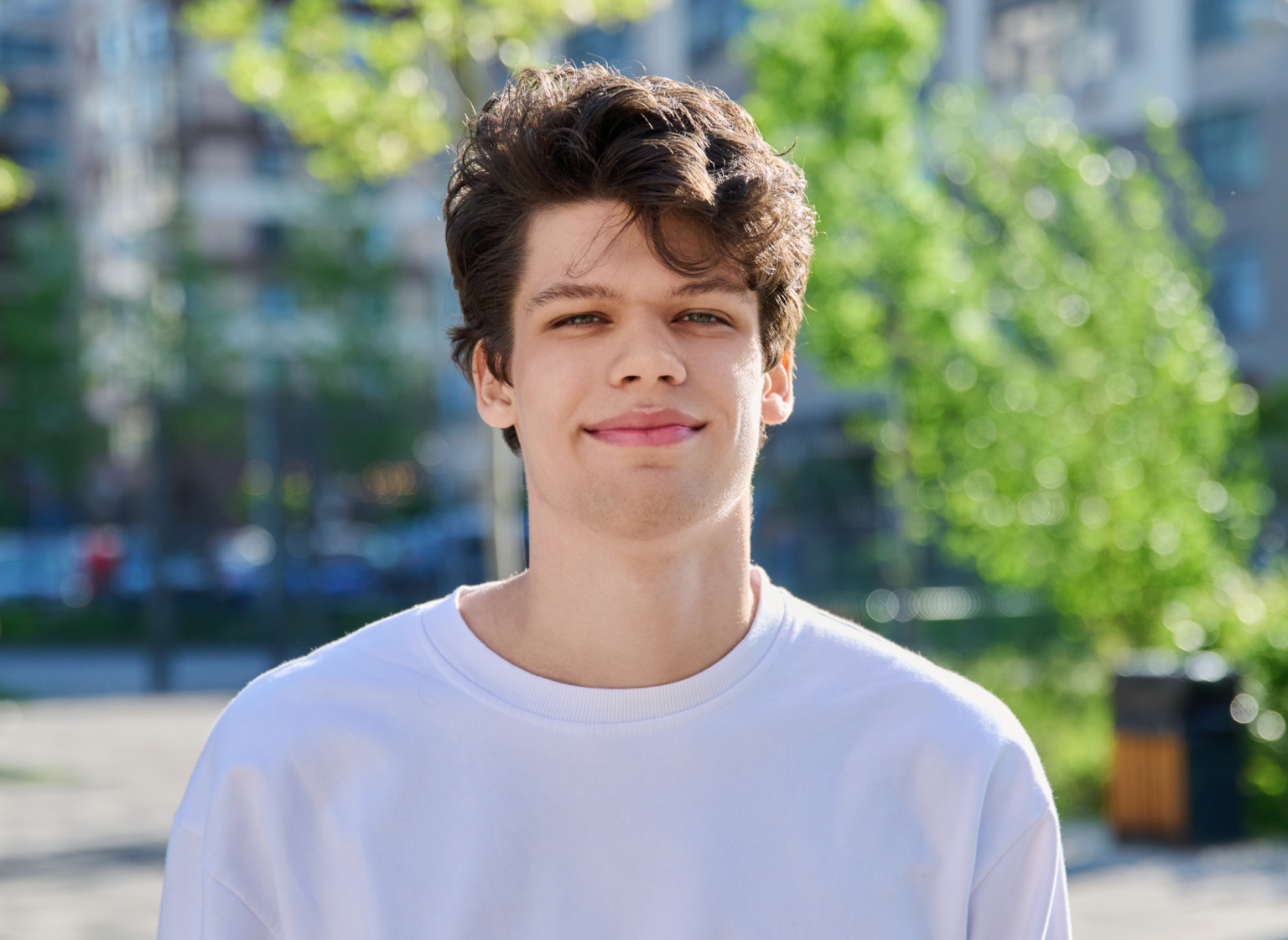 A young man Liam, stood outside wearing a white t-shirt