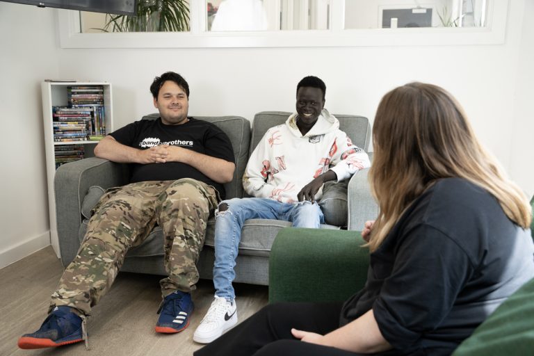 World Mental health and world homeless day image: two young people sat on a sofa smiling