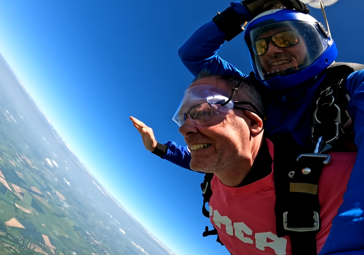 Two men doing a tandem skydive, both are falling through the sky with their arms stretched out to the side.