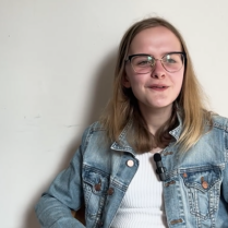 Emi, e-wellbeing Youth Mental Health champion smiling, waring a denim jacket and white t-shirt