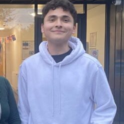 One of our Youth Matters Awards nominees, Randy, smiling in a hoody outside a YMCA building