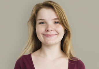 Stacy, a teenage girl with blonde hair smiling, wearing a red top.