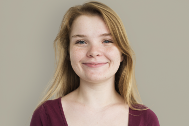 Stacy, a teenage girl with blonde hair smiling, wearing a red top.