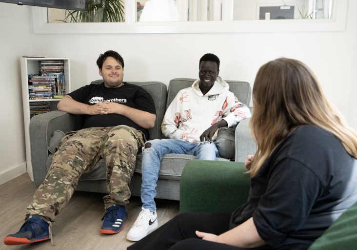 World Mental health and world homeless day image: two young people sat on a sofa smiling